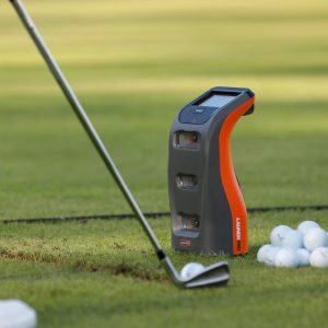 Bushnell Launch Pro beside a golf ball as an iron strikes it