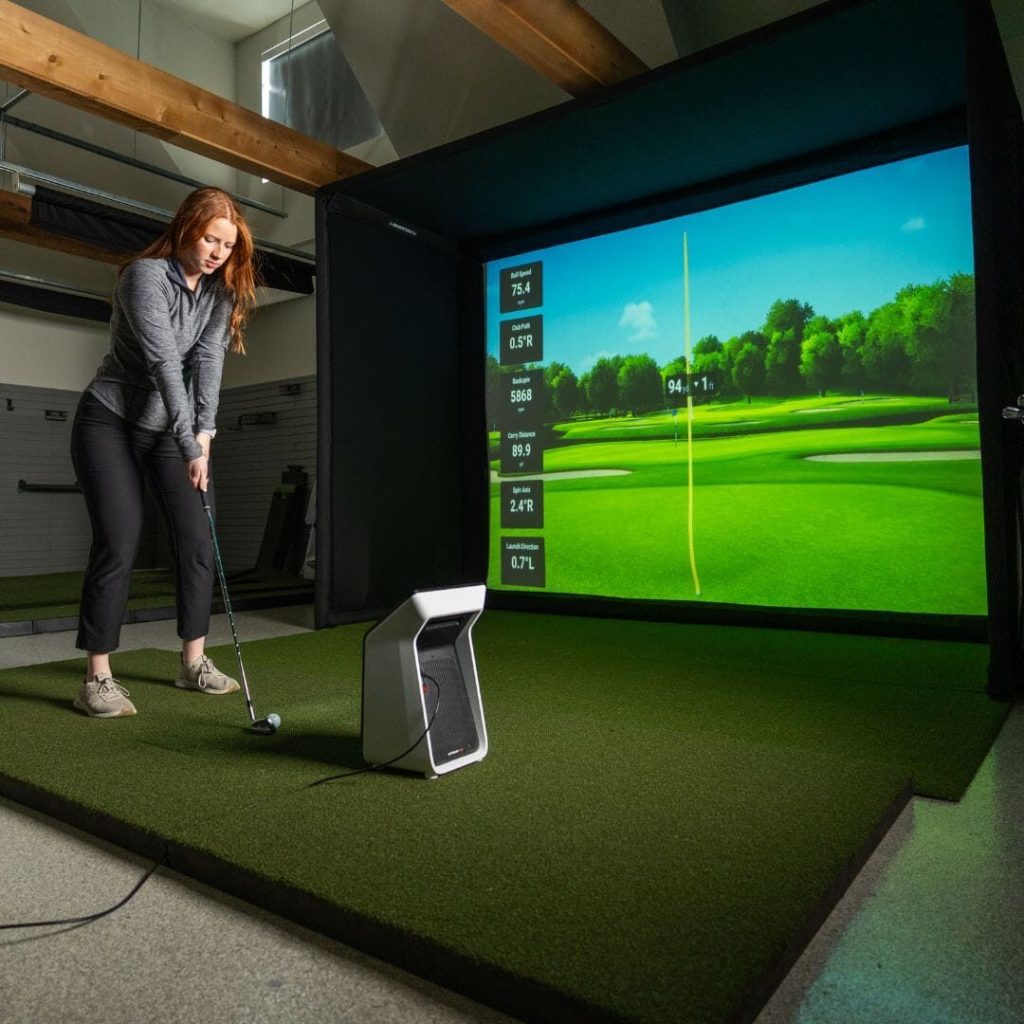 Does Golf Simulator Practice Improve Your Game on the Course? What Carries Over (2026) 1 A golfer hitting from a mat into a home simulator screen