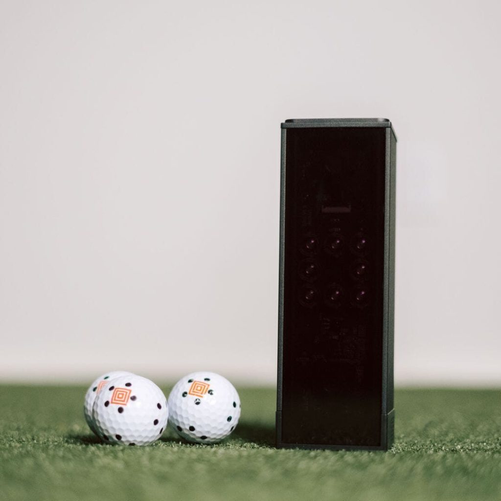 Best Launch Monitor Under $1,000 (2026): Picks by Room and Software Bill 1 Square Golf Home Edition launch monitor on turf next to two marked golf balls