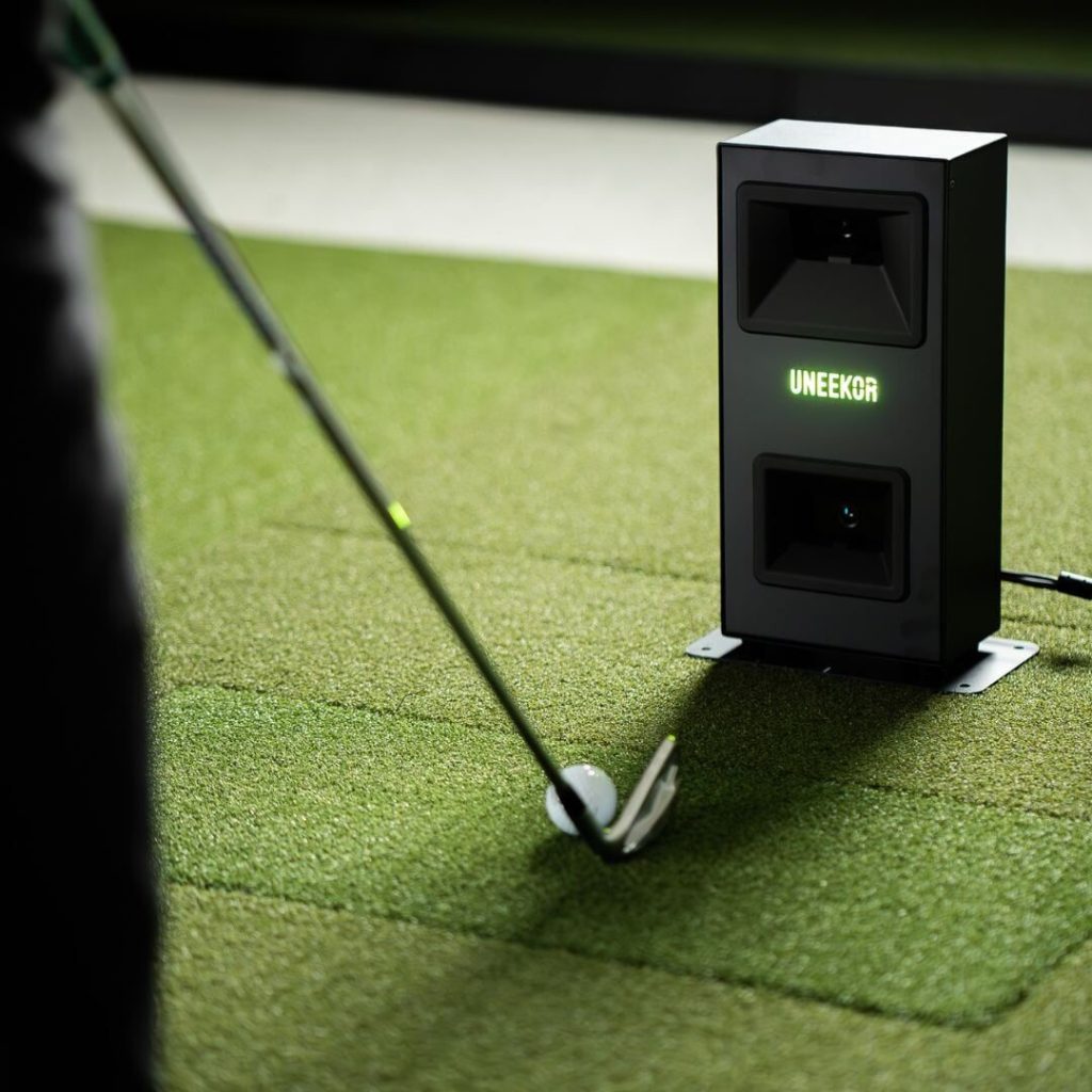 Uneekor EYE MINI LITE on the floor beside the ball as an iron strikes it